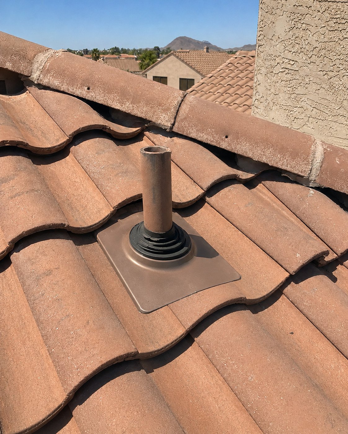 The same penetration with a new colour-matched pipe flashing installed and the tile relaid around it