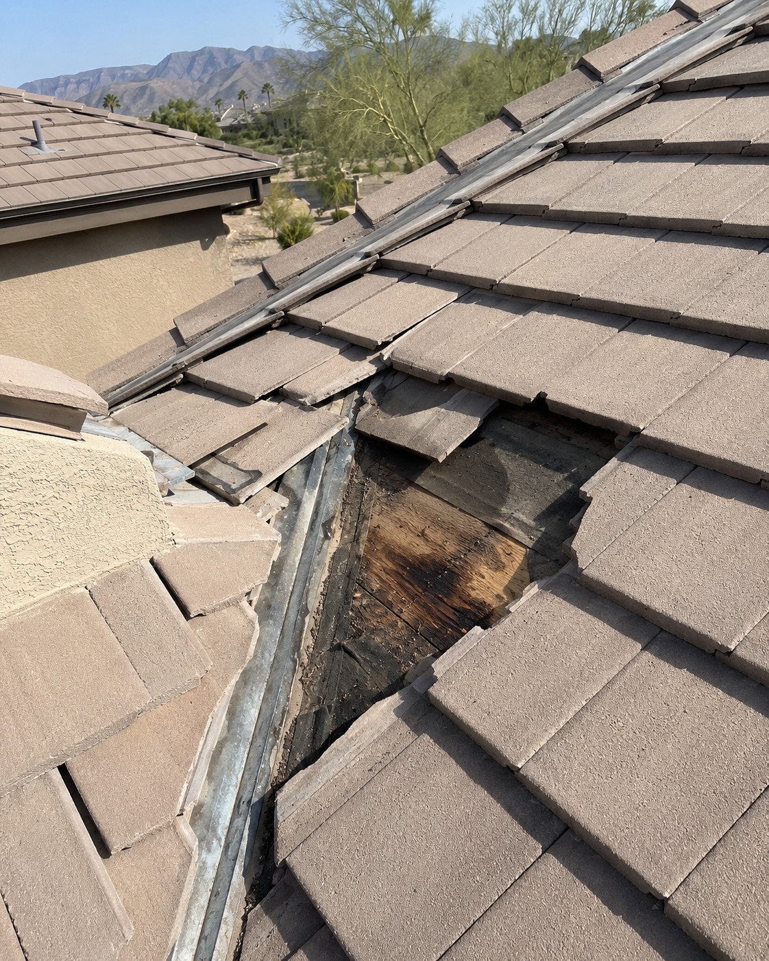 Concrete tile roof opened at a valley, showing broken tiles and water-stained roof decking underneath