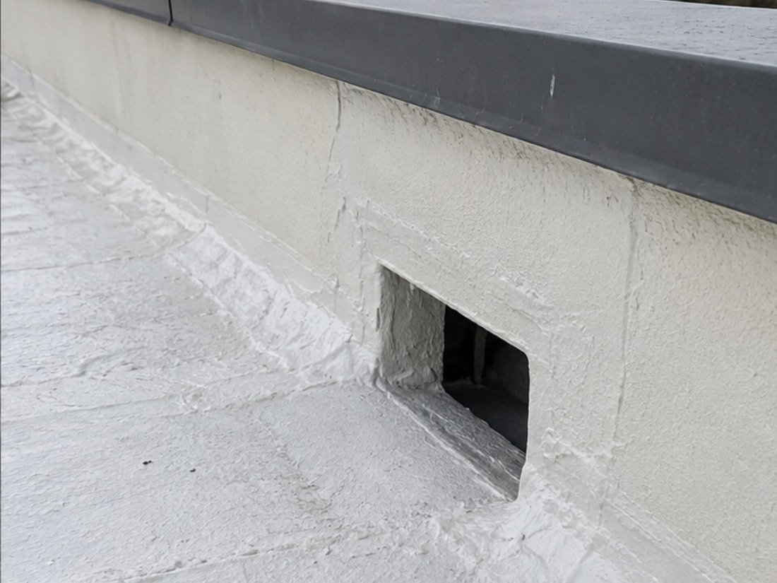 Parapet scupper re-detailed and recoated after a leak